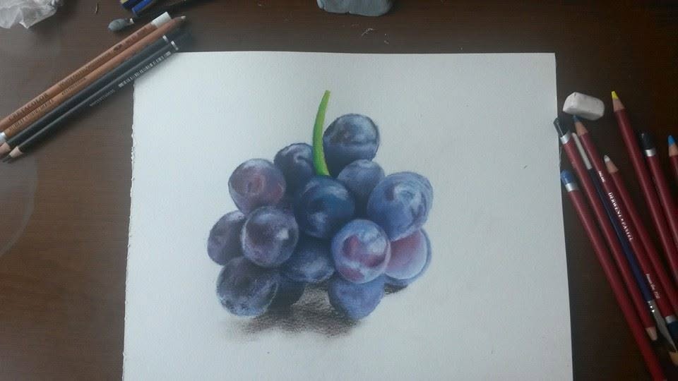 A colored-pencil drawing of grapes, with pencils beside the paper